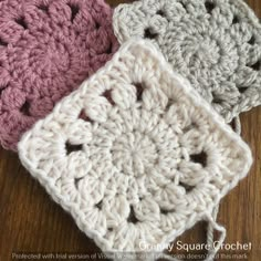 three crocheted squares sitting on top of a wooden table