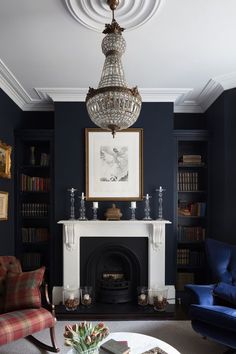 a living room filled with furniture and a fire place under a chandelier above a fireplace