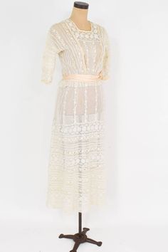 "~ 1900s beautiful tiered ivory lace sheer dress ~ Delicate pretty vintage dress ~ Perfect for a wedding dress ~ Sheer netting, insertion lace ~ 2 layer skirt ~ 28\" Peach satin waist sash ~ 2 \" peplum at waist ~ Back buttons and snaps Condition: Good but there are couple places with tiny holes. Priced accordingly Bust- 34\" (86.5 cm) Shoulder- 16.5\" (42 cm) Sleeve- 11\" (26 cm) Waist- 24\" (61 cm) Hips- 48\" (122 cm) Length Top skirt- 49\" (124.5 cm) Length under skirt- 51\" (129.5 cm) More I Sheer Cream Lace Dress, Feminine Sheer Lace Dress For Wedding, Feminine Sheer Lace Wedding Dress, Delicate Cream Lace Dress, White Victorian Lace For Vintage Events, Victorian White Lace For Vintage Events, Delicate Cream Dress With Lace Details, Delicate Cream Dress With Delicate Lace, Delicate Cream Dress With Lace