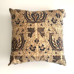 a decorative pillow with blue and brown designs on it's sides, sitting against a white wall