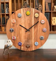 a wooden clock with several different bottle caps on the face and bottom, along with a bird figurine