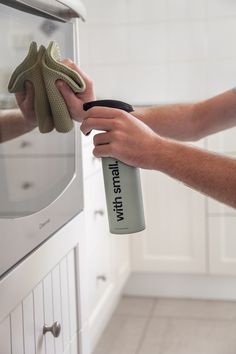 a person is cleaning the oven with a spray bottle and mitt in their hand