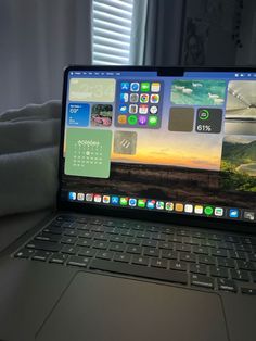 an open laptop computer sitting on top of a table next to a window with white curtains