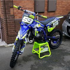 a blue and yellow dirt bike parked next to a car