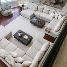 a living room filled with white couches and tables on top of a hard wood floor