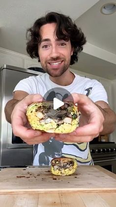 a man holding up a sandwich in front of him on a kitchen counter top with an oven