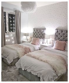 two beds with fluffy blankets and pillows in a white room next to a large window