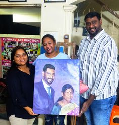 two people standing next to each other holding up a painting with a man and woman on it