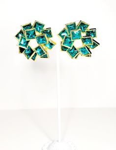 These mesmerizing teal green and gold earring studs will instantly elevate your style game. Adorned with square-shaped green rhinestones, they exude elegance, sophistication, and a touch of whimsical charm. Embrace the beauty of these earrings and make a statement that truly sparkles! Green Metal Earrings For Evening, Trendy Green Earrings For Evening, Green Clip-on Jewelry For Party, Glamorous Green Metal Jewelry, Green Metal Evening Earrings, Glamorous Green Crystal Earrings For Party, Glamorous Green Jeweled Earrings, Green Jeweled Crystal Earrings Gift, Luxury Festive Emerald Earrings