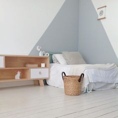 a bedroom with a bed, dresser and shelf in it's corner next to a basket on the floor