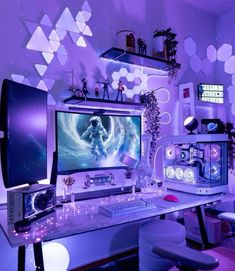 a computer desk topped with a monitor and a keyboard next to a chair in front of a purple wall