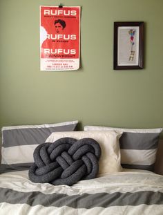 a bed with two pillows on top of it and a poster above the headboard