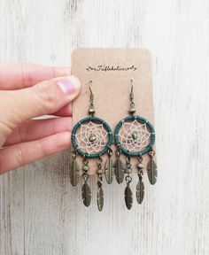 a pair of earrings with feathers hanging from it's earring hooks on top of a card