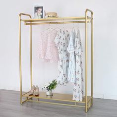 an ironing rack with clothes hanging on it and a potted plant next to it