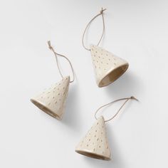 three white ceramic hanging bells with brown polka dots on the top and one has a string attached to it