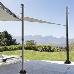 two black and white umbrellas sitting on top of a cement floor next to a lush green field