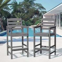 two chairs sitting next to each other in front of a pool