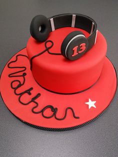 a red birthday cake with headphones on top and the number thirteen written on it