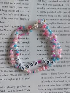 a bracelet that says london on it and is decorated with pink, blue, and white beads