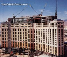 a large building under construction in the middle of a city with cranes on it's roof