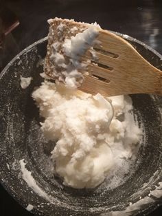 a wooden spatula in a bowl filled with whipped cream and powdered sugar on top