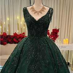 a green ball gown on display in front of red roses