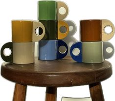 several different colored cups sitting on top of a wooden table next to each other,