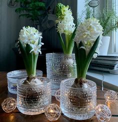 three clear vases with flowers in them sitting on a table next to each other