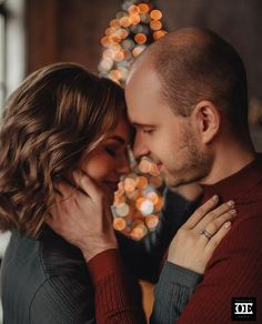 a man and woman embracing in front of a christmas tree