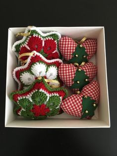 a white box filled with christmas ornaments on top of a black table next to a red and white checkered pillow