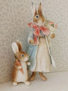 two rabbits are standing next to each other in front of a wallpapered background