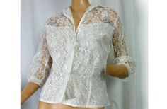 "Lovely lavish lace off white lace blouse/ jacket.  Has that rich Victorian revival style. Perfect for evening wear or wedding. Romantic Gunne Sax look. NOS never worn with store tags attached. Exquisite!  - off white floral and swirl pattern lace - modesty lining at the lower part, sheer shoulders and back - large round covered button and one small clear button at the front - sheer lace sleeves with narrow cuffs - princess fitting seams for body hugging fit - label - A Capri Original - size 36 Elegant Formal Lace Top With Lace Work, Vintage Lace Blouse For Formal Occasions, Elegant Fitted Blouse With Scalloped Lace, Classic Fitted Lace Top For Formal Events, White Feminine Lace Top For Formal Occasions, Formal Fitted Blouse With Scalloped Lace, Feminine Formal Lace Top, Formal Feminine Lace Top, Elegant Delicate Lace Top For Formal Occasions