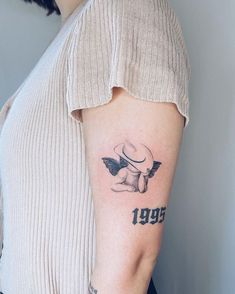 a woman with a tattoo on her arm that reads, 1950 and has an angel