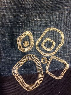 three pairs of gold metal rings sitting on top of a blue piece of cloth with holes in the middle