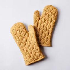 two oven mitts sitting next to each other on top of a white countertop