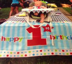 a baby sitting in a highchair at a birthday party