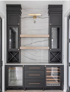 a kitchen with marble counter tops and black cabinetry, along with wooden shelves that have wine glasses on them