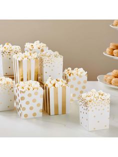 popcorn boxes filled with white and gold polka dotty paper are sitting on a table