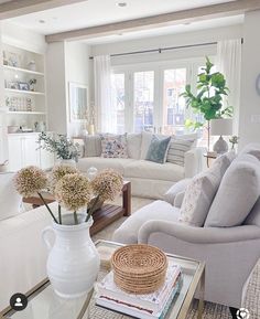 a living room filled with white furniture and lots of flowers on top of a coffee table