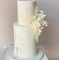 a three tiered white wedding cake with flowers on top