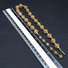 *Description: This is a beautiful clear Murano Italian glass beaded necklace made in the 1930s and filled with flecks of copper & gold which looks like glitter. Gold and copper within the beads is referred to as Aventurine. The necklace was designed with 20 12mm beads separated by clear and gold seed beads. There are six 8mm beads which are wire wrapped to add a matching extension chain. These are gorgeous Venetian beads and as a bead collector, these are one of my favorites. It is a beautif Vintage Glass Faceted Beads, Vintage Polished Gold Beads, Vintage Gold Polished Beads, Vintage Large Gold Beads, Vintage Clear Glass Necklaces, Vintage Clear Glass Necklace, Vintage Clear Round Necklace, Vintage Glass Spacer Beads Jewelry, Vintage Gold Beaded Necklace With Faceted Beads