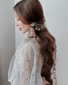 a woman with long brown hair wearing a white dress and gold jewelry on her head