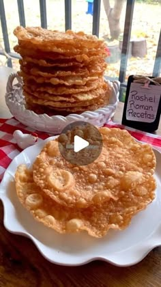 a stack of pancakes sitting on top of a white plate next to a red and white checkered table cloth