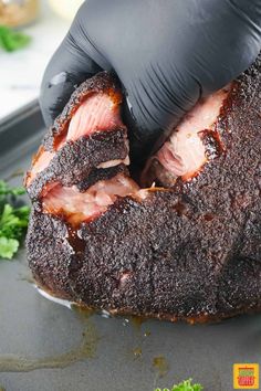 a person in black gloves is cutting up some meat