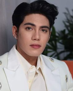 a man with black hair wearing a white suit