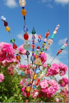 there are many colorful beads on the top of this pole in front of pink flowers