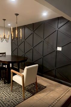 a dining room table and chairs in front of a black paneled wall with chandeliers