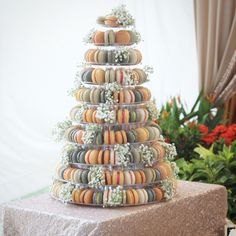 a tower of macaroni and cheese pastries on a table next to potted plants