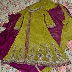 a green and purple dress sitting on top of a bed