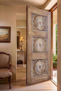 an open door leading to a living room with a chair and painting on the wall